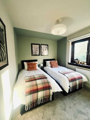 A bedroom with two beds, a window with a view, and artwork on the wall. - Bright and Central Paisley Flat Fast Airport and Glasgow Links (Renfrewshire)