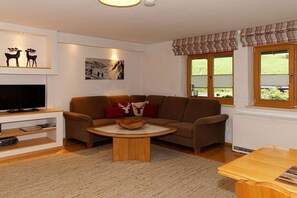 A living room with a sofa, a coffee table, a flat-screen TV, and a fireplace. - "Fellhorn" in the Schneider house (Riezlern)