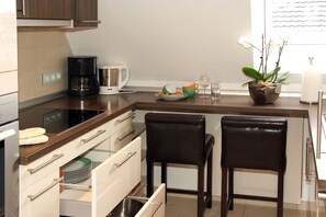 A kitchen with a coffee maker, a kettle, and a potted orchid on the counter. - Holiday apartment with 2 bedrooms (Butjadingen)