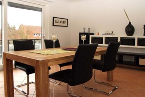 Un comedor con una mesa de madera, sillas negras y un aparador de vidrio con objetos decorativos.