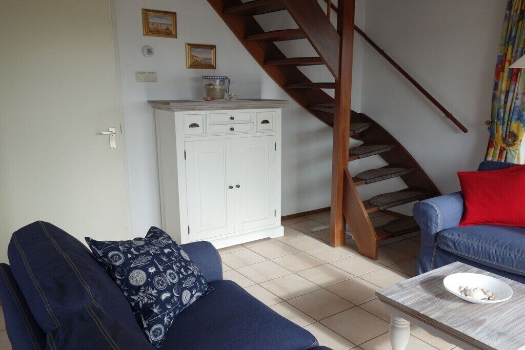 Ein Wohnzimmer mit einer Couch, einem Couchtisch, einem Schrank und einer Treppe.