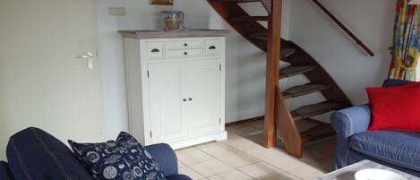 Ein Wohnzimmer mit einer Couch, einem Couchtisch, einem Schrank und einer Treppe.