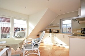 A kitchen with a dining area, including a table and chairs, and a view through a window. - Holiday apartment with 1 bedroom (Norddeich)