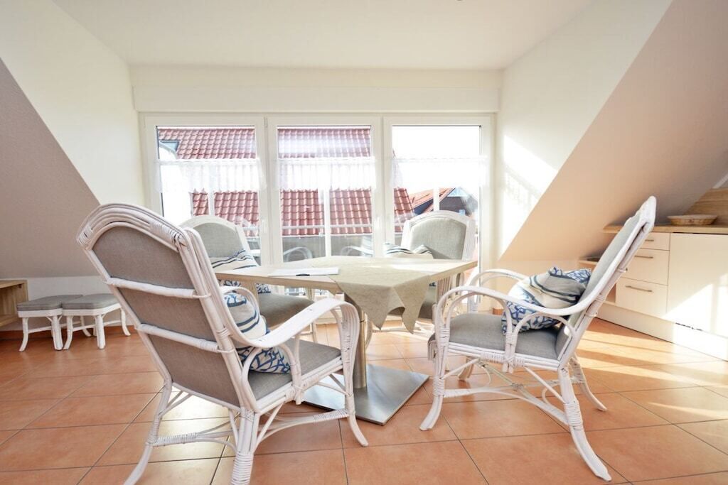 A dining area with a table and chairs, a window with curtains, and a view of buildings outside.