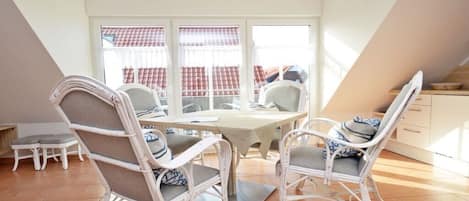 Un comedor con una mesa y sillas, un ventanal con cortinas y vistas a edificios.