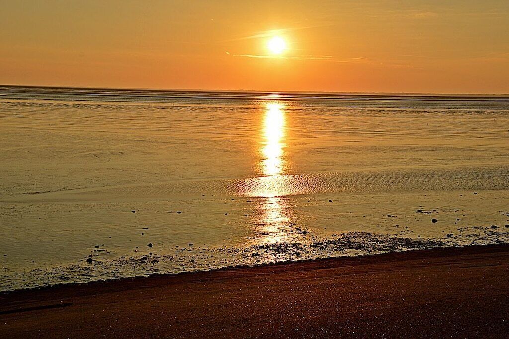 Escena de platja amb un atardeciment sobre l'oceà.