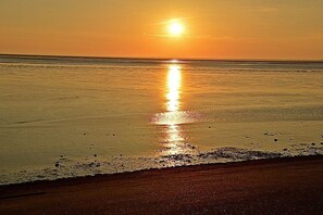 A beach scene with a sunset over the ocean. - Holiday apartment with 1 bedroom (Norddeich)