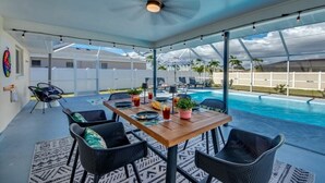Eine Außenpatio mit Pool, einem Esstisch und einem Deckenventilator.