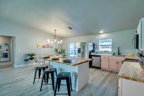 A modern kitchen with a central island, bar stools, and a dining area. - Villa in Cape Coral with swimming pool (Cape Coral)