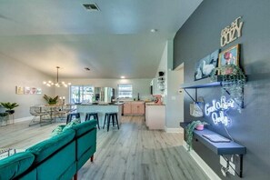 Une cuisine moderne avec un îlot central, des tabourets de bar et un néon mural.