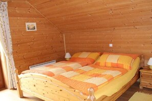 Ein Zimmer mit Holzwänden, einem Bett, zwei Nachttischen und einem kleinen Bild an der Wand.