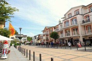 A pedestrian area with buildings, a flag, and a kiosk. - "Beach chair" at the Baltic Sea resort Sandburg (Kühlungsborn)
