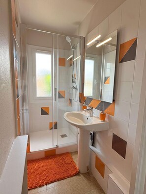 A modern bathroom with a glass shower enclosure, a white sink, and a large mirror. - Cozy studio in the heart of Charnay (Charnay-lès-Mâcon)