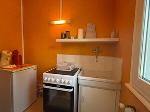A compact kitchen with a stove, oven, and a small countertop. - Cozy studio in the heart of Charnay (Charnay-lès-Mâcon)