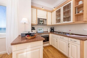 Eine Küche mit weißen Schränken, einer Arbeitsplatte aus Granit, einer Mikrowelle, einer Kaffeemaschine und einer Obstschale.