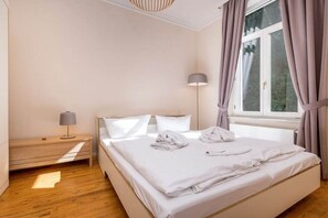 Ein Schlafzimmer mit Bett, Nachttisch, Lampe und einem Fenster mit Vorhängen.