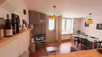 Een gezellige woonruimte met een houten tafel, een televisie en een wijnrek met flessen.