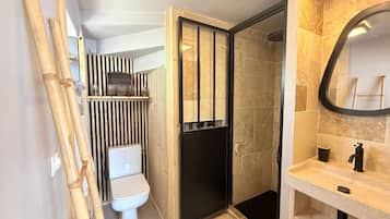 Een moderne badkamer met toilet, douche en wastafel.