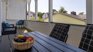 Ein überdachter Außenbereich mit Tisch, Stühlen und einer Fruchtkorb.