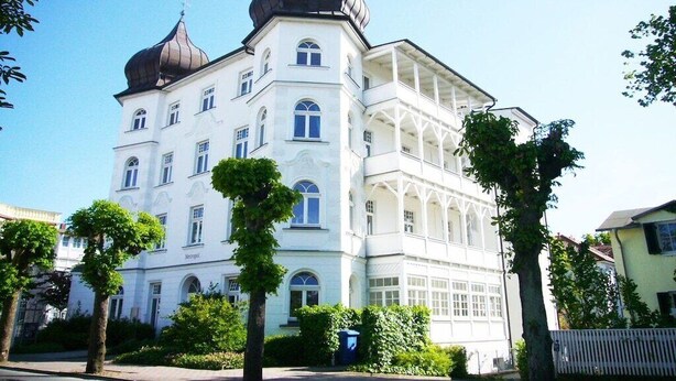 Ein großes, mehrgeschossiges Gebäude mit einer markanten, zentralen Kuppel und kleineren Kuppeln an den Ecken.