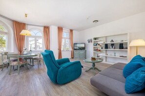A modern living room with a sofa, armchair, and dining table. - "Charlotte" at Villa Metropol (Binz)