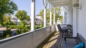 Eine überdachte Veranda mit Tisch und Stühlen, die auf ein Wohngebiet mit Häusern und Grünflächen blickt.