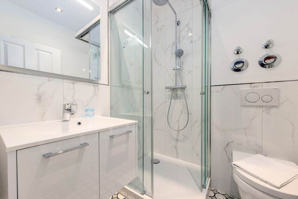 A modern bathroom with a glass-enclosed shower, a white sink, and a toilet.