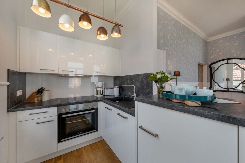 Eine moderne Küche mit weißen Schränken, einer schwarzen Arbeitsplatte und einem eingebauten Backofen.