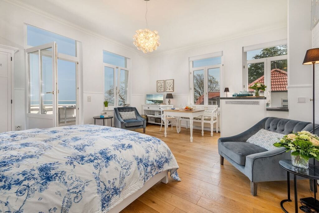 Ein geräumiges Schlafzimmer mit einem großen Bett, einem Schreibtisch und einem grauen Sessel.