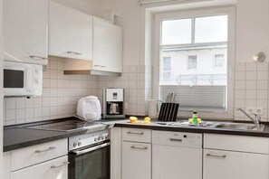 Eine moderne Küche mit weißen Schränken, einem Einbauofen, einer Mikrowelle und einer Kaffeemaschine.