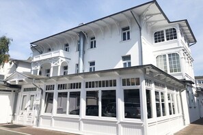 A white building with a large bay window and a garage door. - "Herrenchiemsee 5", Villa Alba (Binz)