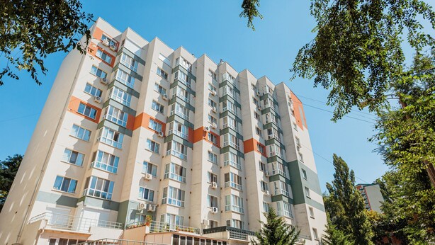 Un edificio residencial de varios pisos con balcones, unidades de aire acondicionado y una entrada con reja.