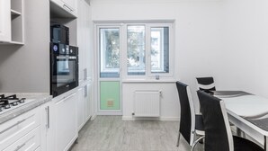 Una cocina moderna con armarios blancos, horno empotrado, estufa a gas y ventana con vista a árboles.
