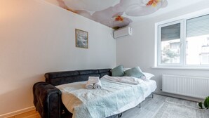 Un dormitorio con cama, radiador, ventana y una planta.