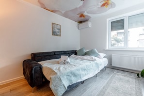 A bedroom with a bed, a radiator, a window, and a plant.