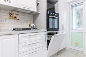 Una cocina moderna con armarios blancos, horno empotrado y lavavajillas.