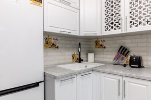 A kitchen with white cabinets, a sink, a faucet, and a toaster.