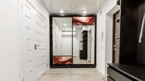 Un pasillo con una puerta espejo, una encimera negra y un suelo de madera claro.