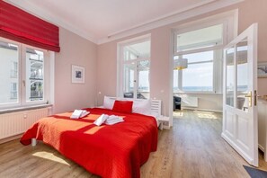 Hotellihuone, jossa on suuri sänky, ikkunasta avautuva kaunis näköala ja ovi, joka johtaa parvekkeelle.