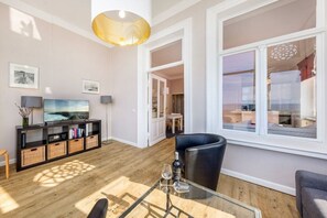A modern living room with a glass coffee table, a flat-screen TV, and a comfortable seating area. - Stella Maris, Villa Agnes (Binz)