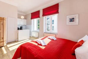 A room with a bed, a window with red valances, a white cabinet, and a framed picture on the wall. - Stella Maris, Villa Agnes (Binz)