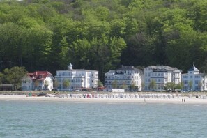 A coastal hotel with multiple buildings, a beach, and a forested hillside. - Stella Maris, Villa Agnes (Binz)