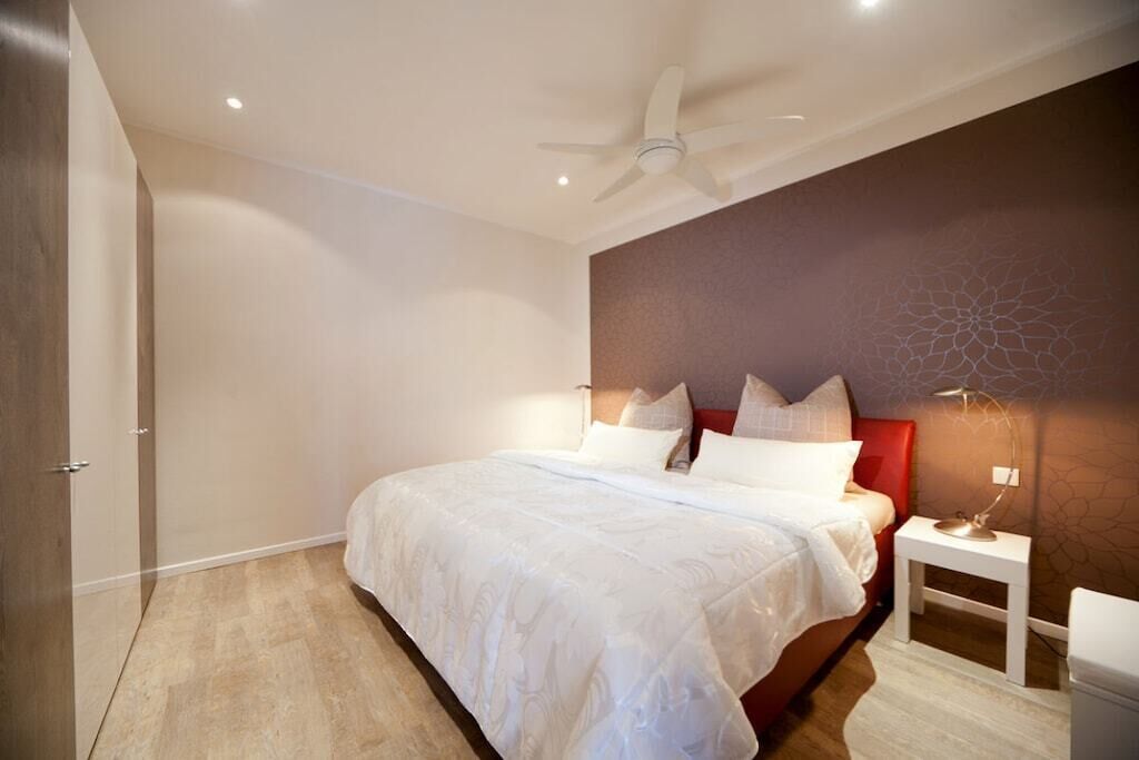A bedroom with a bed, a nightstand, a lamp, and a ceiling fan.