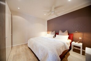 Ein Schlafzimmer mit einem Bett, einem Nachttisch, einer Lampe und einem Deckenventilator.