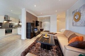 Ein modernes Wohnzimmer mit einer Couch, einem Couchtisch und einer Küche im Hintergrund.