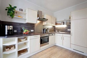 Eine moderne Küche mit weißen Schränken, einem eingebauten Backofen und einer Edelstahl-Dunstabzugshaube.
