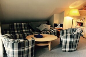 A cozy living room with a sofa, two armchairs, a coffee table, and a lamp. - Beach villa Miramare, apartment Seepferdchen (Ostsee Bad Boltenhagen)