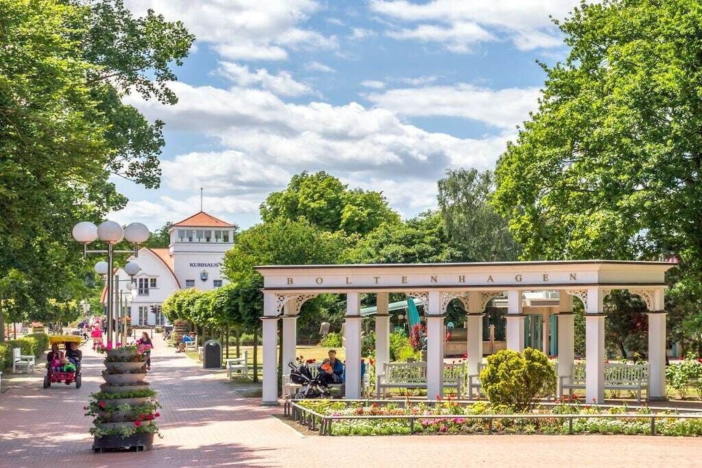 A gazebo with the inscription 'BOLTENHAAGEN' in a park setting with trees and a building in the background.