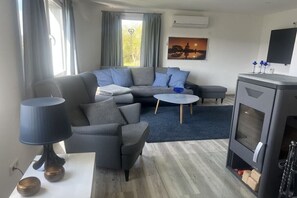 Ein modernes Wohnzimmer mit einem grauen Sofa, einem runden Couchtisch, einer Lampe und einem Kamin.