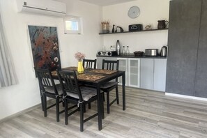 A dining area with a table and chairs, a kitchen with cabinets and appliances, and a clock on the wall. - Holiday home in Quedlinburg with barbecue (Quedlinburg)